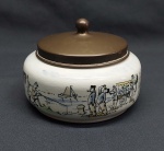Pote redondo em porcelana holandesa na cor branca, pintado a mão com cenas da cidade. Tampa em metal bronzeado. Marcado GOUDA - HOLLAND. Med. 10 x 14 cm.