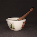 Almofariz em cerâmica esmaltada na cor branca, decorado com selos postais de diversas nacionalidades. Pistilo com cabo de madeira. Marcado. Diam. 9,5 cm.