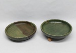 Duas petisqueiras em madeira com pátina verde, uma delas com pés trípodes esféricos. Diam. 19 cm.