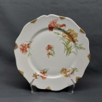 Prato decorativo em porcelana francesa na cor branca, borda recortada, decorado com Cravos coloridos, douração. Marcado LIMOGES - FRANCE. Diam. 25 cm.