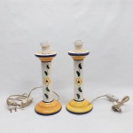 Par de luminárias de mesa confeccionado em cerâmica vitrificada, haste esmaltada com flor e folhagens. Base e borda com barrado na tonalidade amarela e frisos azuis. Cúpula em pergaminho branco. Alt. Total 38 cm.