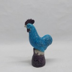 Tradicional estatueta de galo confeccionado em porcelana na tonalidade azul turquesa. Ao gosto Companhia das Índias. Alt. 16 cm. (bicado no bico).