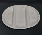 Graciosa petisqueira confeccionada em porcelana branca, com três divisórias, moldada na pasta. Adornada na borda com frutos e folhagens. Medidas: 41,5 x 29 cm.