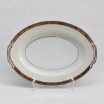 NORITAKE - Travessa em porcelana japonesa decorada com faixa creme, borda em ouro brunhido e canetado em preto com flores e folhagens. Marca da Manufatura no fundo. 30 x 23cm.