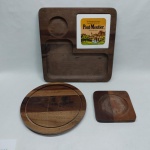 Três peças em madeira: A) Queijeira (falta a tampa) e petisqueira. Med. 28 cm e 16 x 16 cm. B) Bandeja com suporte p/ queijos em porcelana esmaltada e nichos p/ petisqueiras. Med. 35 x 35 cm.