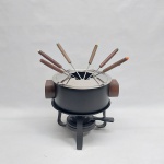 Aparelho p/ fondue em metal revestido de material antiaderente, pegas em madeira. Acompanha seis  garfinhos e dois queimadores. Alt. 21 cm.