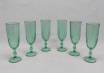 Seis flutes p/ champanhe em vidro verde, base redonda, haste balaustre e bojo moldado no padrão dedão. Alt. 17,5 cm.
