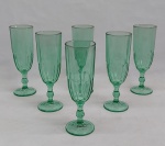 Seis flutes p/ champanhe em vidro verde, base redonda, haste balaustre e bojo moldado no padrão dedão. Alt. 17,5 cm.