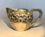 Leiteira em prata portuguesa  contraste Águia. Elegante leiteira em prata portuguesa contrastada (833), pertencente ao mesmo conjunto de bules e açucareiro descritos nos lotes anteriores. Corpo bojudo com rica decoração repuxada e cinzelada em volutas, concheados e elementos florais, com interior dourado e bico largo ornamentado por volutas e guirlandas gravadas. Apresenta punções oficiais portugueses com a marca da Águia, indicando teor de 833 milésimos, e punção adicional em forma pentagonal referente ao ensaiador. Peça de grande harmonia formal e fino acabamento, típica da ourivesaria portuguesa de fim do século XIX, produzida para serviços de chá e café de prestígio. Medidas: 15,5 cm (comprimento total) x 12,5 cm (altura) x 10 cm (diâmetro máximo).Material: Prata portuguesa contrastada (833).Peso: 278 gr. Procedência: Acervo família Rezende  residência Av. Atlântica, Copacabana  Rio de Janeiro.