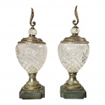 METAL PRATEADO /  ESTANHO E CRISTAL - Par de potiches em metal prateado, estanho e cristal moldadoEuropa, circa 1920/40.Conjunto formado por duas urnas decorativas de corpo ovóide em cristal moldado e lapidado em padrão de losangos e estrelas, montadas sobre bases quadradas escalonadas em liga de estanho e chumbo, com frisos perolados e guarnições douradas. Tampas em metal prateado, encimadas por pináculos em forma de chama estilizada e esferas de cristal facetado. Peças de refinado trabalho artesanal, evocando o gosto neoclássico revival típico da Belle Époque.Presença de sinais do tempo e oxidação nas bases.Medidas: 43 cm de altura; base 12 x 12 cm.HISTÓRIA - Urnas com tampa, muitas vezes chamadas de vasos ou jarras, têm uma longa história em artes decorativas, servindo a fins funcionais e estéticos.Historicamente, eles eram usados para armazenar itens preciosos ligados a práticas funerárias ou como peças ornamentais em grandes casas. A combinação de vidro cortado e metalurgia tornou-se particularmente popular durante o século XIX e início do século XX, refletindo avanços na fabricação de vidro e técnicas de fundição de metal. Necessitam restauração. Leve bicado na borda de uma das taças de cristal (vide foto complementar).