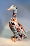 ARTE ORIENTAL - Figura de pato em porcelana chinesa, Dinastia Qing (16441912), decoração estilo Imari.Escultura zoomórfica em porcelana - meados do século XX - representando pato em posição ereta, de corpo alongado e delicadamente modelado. Decoração em esmaltes sobre o vidrado, com flores estilizadas nas cores ferro-vermelho, azul-cobalto e dourado, enriquecidas por toques de verde-turquesa - composição que remete diretamente à paleta Imari japonesa, reinterpretada pelos fornos chineses no período final da Dinastia Qing.Medidas: 28 cm de altura x 18 cm de comprimento x 16 cm de largura máxima.Em excelente estado geral de conservação.Faz conjunto com os dois lotes subsequentes.Nota histórica:A estética Imari, originária da região de Arita (Japão), alcançou enorme popularidade na Europa do século XVIII e foi amplamente reinterpretada pelos ceramistas de Jingdezhen, na China. Essas versões exibem equilíbrio entre exuberância oriental e gosto ocidental por composições florais densas, sendo peças muito exportadas pela Companhia das Índias.Nota técnica  marca de base:Na base, inscrição em azul sob o vidrado com os caracteres  (Zhn y cáng wán), traduzidos como Peça de coleção preciosa e elegante. Trata-se de marca de oficina contemporânea, utilizada em produções decorativas pós-1949, inspiradas na porcelana Qing e destinadas ao mercado de exportação.Estatuetas de porcelana chinesa, particularmente aquelas que retratam animais como patos, têm uma longa e rica história, muitas vezes imbuída de significado simbólico. Os patos, especialmente os patos mandarim, são frequentemente associados à fidelidade conjugal e boa sorte na cultura chinesa. O estilo decorativo visto nesta estatueta - ora ofertada em nosso leilão - com seus padrões florais vibrantes em azul e laranja, lembra a paleta 'Imari', que foi popularizada na China e no Japão e amplamente exportada para a Europa.Este estilo particular de decoração, muitas vezes referido como Imari chinês, floresceu durante a Dinastia Qing (1644-1912). Tais peças eram muito procuradas por colecionadores europeus e muitas vezes eram produzidas em grandes quantidades para exportação. O artesanato, incluindo os detalhes pintados à mão e o esmalte brilhante, indica um artesão habilidoso, e a estética geral é característica da porcelana decorativa produzida tanto para uso doméstico quanto para o comércio internacional durante este período.