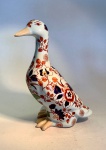 ARTE ORIENTAL - Figura de pato em porcelana chinesa, Dinastia Qing (16441912), decoração estilo Imari.Escultura zoomórfica em porcelana - meados do século XX - representando pato em posição ereta, de corpo alongado e delicadamente modelado. Decoração em esmaltes sobre o vidrado, com flores estilizadas nas cores ferro-vermelho, azul-cobalto e dourado, enriquecidas por toques de verde-turquesa - composição que remete diretamente à paleta Imari japonesa, reinterpretada pelos fornos chineses no período final da Dinastia Qing.Medidas: 22cm de altura x 16 cm de comprimento x 12 cm de largura máxima.Em excelente estado geral de conservação.Faz conjunto com o  lote anterior e o subsequente. Nota histórica:A estética Imari, originária da região de Arita (Japão), alcançou enorme popularidade na Europa do século XVIII e foi amplamente reinterpretada pelos ceramistas de Jingdezhen, na China. Essas versões exibem equilíbrio entre exuberância oriental e gosto ocidental por composições florais densas, sendo peças muito exportadas pela Companhia das Índias.Nota técnica  marca de base:Na base, inscrição em azul sob o vidrado com os caracteres  (Zhn y cáng wán), traduzidos como Peça de coleção preciosa e elegante. Trata-se de marca de oficina contemporânea, utilizada em produções decorativas pós-1949, inspiradas na porcelana Qing e destinadas ao mercado de exportação.Estatuetas de porcelana chinesa, particularmente aquelas que retratam animais como patos, têm uma longa e rica história, muitas vezes imbuída de significado simbólico. Os patos, especialmente os patos mandarim, são frequentemente associados à fidelidade conjugal e boa sorte na cultura chinesa. O estilo decorativo visto nesta estatueta - ora ofertada em nosso leilão - com seus padrões florais vibrantes em azul e laranja, lembra a paleta 'Imari', que foi popularizada na China e no Japão e amplamente exportada para a Europa.Este estilo particular de decoração, muitas vezes referido como Imari chinês, floresceu durante a Dinastia Qing (1644-1912). Tais peças eram muito procuradas por colecionadores europeus e muitas vezes eram produzidas em grandes quantidades para exportação. O artesanato, incluindo os detalhes pintados à mão e o esmalte brilhante, indica um artesão habilidoso, e a estética geral é característica da porcelana decorativa produzida tanto para uso doméstico quanto para o comércio internacional durante este período.