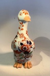 ARTE ORIENTAL - Figura de pato em porcelana chinesa, Dinastia Qing (16441912), decoração estilo Imari.Escultura zoomórfica em porcelana - meados do século XX - representando pato em posição ereta, de corpo alongado e delicadamente modelado. Decoração em esmaltes sobre o vidrado, com flores estilizadas nas cores ferro-vermelho, azul-cobalto e dourado, enriquecidas por toques de verde-turquesa - composição que remete diretamente à paleta Imari japonesa, reinterpretada pelos fornos chineses no período final da Dinastia Qing.Medidas: 19,5 cm de altura x 12 cm de comprimento x 8 cm de largura máxima.Em excelente estado geral de conservação.Faz conjunto com os dois lotes anteriores.Nota histórica:A estética Imari, originária da região de Arita (Japão), alcançou enorme popularidade na Europa do século XVIII e foi amplamente reinterpretada pelos ceramistas de Jingdezhen, na China. Essas versões exibem equilíbrio entre exuberância oriental e gosto ocidental por composições florais densas, sendo peças muito exportadas pela Companhia das Índias.Nota técnica  marca de base:Na base, inscrição em azul sob o vidrado com os caracteres  (Zhn y cáng wán), traduzidos como Peça de coleção preciosa e elegante. Trata-se de marca de oficina contemporânea, utilizada em produções decorativas pós-1949, inspiradas na porcelana Qing e destinadas ao mercado de exportação.Estatuetas de porcelana chinesa, particularmente aquelas que retratam animais como patos, têm uma longa e rica história, muitas vezes imbuída de significado simbólico. Os patos, especialmente os patos mandarim, são frequentemente associados à fidelidade conjugal e boa sorte na cultura chinesa. O estilo decorativo visto nesta estatueta - ora ofertada em nosso leilão - com seus padrões florais vibrantes em azul e laranja, lembra a paleta 'Imari', que foi popularizada na China e no Japão e amplamente exportada para a Europa.Este estilo particular de decoração, muitas vezes referido como Imari chinês, floresceu durante a Dinastia Qing (1644-1912). Tais peças eram muito procuradas por colecionadores europeus e muitas vezes eram produzidas em grandes quantidades para exportação. O artesanato, incluindo os detalhes pintados à mão e o esmalte brilhante, indica um artesão habilidoso, e a estética geral é característica da porcelana decorativa produzida tanto para uso doméstico quanto para o comércio internacional durante este período.