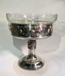 Fruteira de Pé Alto com Cristal LapidadoMetal com banho de prata, em bom estado de conservação, compondo base, fuste e suporte superior ornamentado por frisos e relevo floral em estilo tardo-Art Nouveau.Bacia em cristal transparente recortado e lapidado, com desenho geométrico em leque, sem lascas, trincas ou perdas.Necessita apenas soldagem do elemento do fuste à base metálica.Banho de prata original, em bom estado, dispensando novo prateamento.Medidas: 30 cm de altura x 28 cm de diâmetro.Peça de mesa elegante, de produção europeia da primeira metade do século XX, conjugando metal fundido e cristal prensado em composição harmônica de linhas curvas e acabamento brilhante.