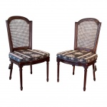 Par de cadeiras estilo Luís XVI em madeira nobre escurecida, manufatura não identificada, meados do século XX. Estrutura em madeira nobre escurecida, com encosto emoldurado em formato reto com coroa superior em semi-círculo de degrau duplo, característico do estilo Luís XVI.Encosto em palhinha indiana natural, original e bem tensionada.Assento solto, forrado em tecido sintético com padronagem clássica em preto e bege, simulando trama de palha natural.As pernas são retas e caneladas, unidas por travessas discretas, apresentando rosetas florais esculpidas nos cantos dos apoios frontais  detalhe distintivo da linguagem neoclássica francesa.Medidas: 100 cm de altura x 53 cm de largura x 55 cm de profundidade.Em bom estado geral de conservação, sem indícios de restauro, colagens, rachaduras ou partes substituídas.Necessitam apenas de leve lustro de realce para devolver brilho à madeira. Faz conjunto com o lote anterior e o lote seguinte.