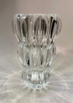 Vaso em cristal RogaskaEslovênia, final do século XXCristal de alto teor de chumbo lapidado, de fabricação Rogaka Crystal  tradicional manufatura eslovena fundada em 1665 e reconhecida mundialmente pela pureza e transparência de seu cristal. Peça de corpo bojudamente facetado em cortes verticais elípticos que criam intensos efeitos prismáticos de luz e sombra. Etiqueta original Rogaka Crystal  Made in Slovenia.Altura: 28 cm. Diâmetro máximo: 16 cm.* Nota do editor: O desenho deste vaso combina monumentalidade e precisão geométrica, refletindo a excelência técnica do cristal esloveno na tradição centro-europeia. As lapidações profundas, de ritmo quase arquitetônico, fragmentam a luz em feixes radiais que se projetam sobre a superfície, resultando em uma presença luminosa de rara intensidade. Peça de destaque para interiores contemporâneos ou clássicos, símbolo de sofisticação e tradição artesanal.