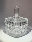 Caixa com tampa em cristal moldadoEuropa, séc. XX (meados)Peça em cristal transparente moldado, corpo e tampa facetados em padrão geométrico de quadrículas em relevo. Pega superior facetada em forma de pináculo, esmeradamente lapidada.Medidas: 13,5 cm de altura (com tampa); 11 cm de diâmetro.Condição: excelente, sem bicados aparentes.Leitura: modelo de linha decorativa europeia de meados do século XX, inspirado nas criações art déco, com ênfase na simetria e no brilho das superfícies em relevo.