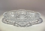 Petisqueira em cristal moldado tchecoRepública Tcheca, séc. XX (meados)Peça em cristal transparente moldado, formato orgânico de borda recortada em zigue-zague, com decoração em relevo composta por estrelas e losangos entre arcos. Fundo com estrela central lapidada, típica da tradição boêmia.Medidas: 18 x 12,3 cm.Modelo clássico de produção tcheca do pós-guerra, representando o refinamento das oficinas de cristal da Boêmia, onde o corte geométrico e a refração da luz são tratados como linguagem ornamental.Condição: excelente, sem bicados.