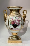PORCELANA EUROPEIA -  Vaso decorativo / Limoges, FrançaAssinado Massou 1813. Porcelana fina francesa moldada e pintada à mão, corpo ovóide sobre base quadrada, alças modeladas em forma de cabeças de cisne e acabamento integral em douração de alto brilho.Painéis frontais e posteriores com reservas florais policromadas, enquadradas por filetes dourados.Marca em verde sob o vidrado: LIMOGES  Made in France.Medidas: 24,5 cm de altura x 18 cm de largura x 8 cm de espessura.Exemplar inspirado nos vasos Empire de Sèvres, típico das produções de Limoges do fim do século XIX e início do XX, com decoração em estilo neoclássico e assinatura alusiva a Massou 1813  em referência comemorativa de modelos originais do período napoleônico.Condição: douração com leves desgastes coerentes à idade. Necessita aperto na porca rosqueara que que une o corpo a base a partir de um fuso. Perda (lasca) em ponto de junção - necessário restauro. Faz par com o lote anterior.