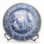 Prato Woodman  Spode Blue Room Collection, Inglaterra. Porcelana inglesa de corpo fino e esmalte branco, com borda levemente ondulada e decoração monocromática em azul sob o vidrado (underglaze blue transferware).Motivo central representando cena campestre com casal e criança em paisagem rural inglesa, cercada por elaborada moldura floral.Marca no verso: The Spode Blue Room Collection  Woodman  First introduced c.1816, acompanhada da menção ao processo de gravação manual em chapa de cobre.Produzido pela Spode, Made in England, referência S3427-Y.Medidas: 26,5 cm de diâmetro.Peça pertencente à renomada Blue Room Collection, que revisita padrões históricos criados pela Spode desde o início do século XIX.A cena, intitulada Woodman, foi originalmente introduzida por volta de 1816, e é um dos motivos mais clássicos do repertório rural vitoriano, celebrando o trabalho e a vida simples no campo.Nota histórica:A Spode, fundada em 1770 em Staffordshire, é considerada a principal responsável pela consolidação da porcelana inglesa de padrão blue and white, introduzindo o uso do transfer printing  processo de impressão sob o vidrado que revolucionou a produção cerâmica europeia ao permitir a reprodução fiel de gravuras em série.A técnica utilizava chapas de cobre gravadas à mão, das quais se transferia o desenho para o corpo cerâmico antes da queima. Essa inovação garantiu à Spode o domínio de uma estética que uniu precisão gráfica, luminosidade e acessibilidade, transformando o azul-cobalto inglês em símbolo de elegância e tradição.A série Blue Room Collection, reeditada no século XX, preserva o rigor histórico e o apelo romântico das primeiras edições de 1816, tornando cada exemplar uma homenagem à era de ouro da porcelana britânica. Fonte: Spode Transfer Printed Ware 17841833 (David Drakard & Paul Holdway) - Guia definitivo da manufatura que trás quase todos os modelos produzidos pela marca. (EBT)