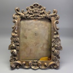 METAL - Lindo porta retrato em metal espessurado a prata, decorado com flores em relevo, arabescos. conchas. Med. 35x30 cm.