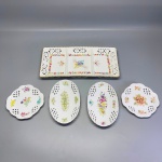 PORCELANA - Conjunto de petisqueiras em porcelanas brancas, pintadas a mão, motivo de flores, vazadas. Med. 31x15 cm e 13 cm. Total de 5 peças.