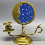 METAL - Lindo castiçal de mão em metal dourado, com suporte giratório ao centro, lua com vidro azul e estrelas, lapidadas, onde se projeta sobra. Med. 20x20 cm. Marcas do tempo e vidro quebrado.