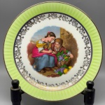 PORCELANA - Prato decorativo em porcelana francesa, LIMOGES decorada com cena central de mulheres colhendo frutos, faixa verde e frisos dourados. Dia. 24,5 cm.