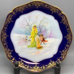 PORCELANA - Prato decorativo em porcelana francesa, LIMOGES, decorada com cena central policromada, representando mulher, crianças e fogueira. Dia. 31 cm.