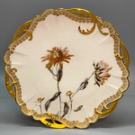 PORCELANA - Prato decorativo em porcelana francesa, LIMOGES, decorada com flores policromadas, borda vazada e ricamente dourado. Dia. 23 cm.