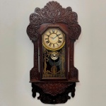 RELÓGIO - Relógio de parede, caixa em madeira nobre, vidro pintado com desenho de laço, mostrador em metal dourado. Med. 55x29x12 cm. Acompanha pêndulo e chave.