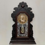 RELÓGIO - Relógio de parede da marca "Ansonia". Caixa em madeira nobre entalhada. Vidro da porta em pintura jateada. E.U.A. Med. 58x37x13 cm. Pêndulo e chave. Não testado e sem garantia.