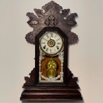 RELÓGIO - Relógio de parede da marca "Ansonia". Caixa em madeira nobre entalhada. Vidro da porta em pintura jateada. E.U.A. Med. 57x37x13 cm. Pêndulo e chave. Não testado e sem garantia.