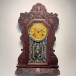 RELÓGIO - Relógio de parede da marca "Ansonia". Caixa em madeira nobre entalhada. Vidro da porta em pintura jateada. E.U.A. Med. 52x38x13 cm. Sem chave.  Não testado e sem garantia.