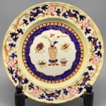 PORCELANA - Prato decorativo inglêsa, branca decorado com vaso e flores policromados. Dia. 26,5 cm.