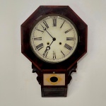 RELÓGIO - Relógio de parede oitavado em madeira nobre, mostrador em metal, algarismos romanos, vidros bisotados, 2 furos. Med. 66x43x11 cm. Não possui chaves. Não testados e sem garantia.