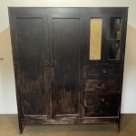 MOBILIÁRIO - Antigo guarda roupa confeccionado em madeira maciça, apresentando uma pátina preta com efeito desgastado, que revela a tonalidade natural da madeira por baixo. Super funcional com duas portas lisas à esquerda e, no lado direito, uma porta superior envidraçada e três gavetas inferiores com puxadores redondos simples. Med. 176x148x55 cm. Marcas do tempo e de uso. Falta um vidro. Móveis Usados - Lote de móvel antigo e usado, podendo apresentar marcas de uso e desgaste natural do tempo. Há possibilidade de danos ocultos e ou outras imperfeições.  Não há garantia ou possibilidade de devolução após a aquisição. Recomenda-se inspeção prévia.
