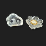 Duas peças executadas em vidro translúcido, sendo uma com relógio encrustado em `flor` e uma gruta com caravela, 8 x 5 e  10 x 9 cm.