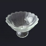 Centro de mesa em cristal, lapidação de flores, bordas babadas e  poá em alto relevo apoiado em haste sustentada por base circular, Alt. 17, Diam. 21 cm.