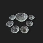 Uma saladeira e  seis bowls em cristal lapidado apoiados em delicados pezinhos, Diam. 26, Alt. 10 e  Diam. 13, Alt. 5 cm.