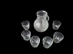 Uma refresqueira em demi cristal canelado e  6 copos de vidro para água ou suco. Alt. 22 e 8 cm.