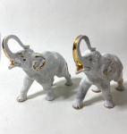 Par de esculturas representando elefantes na cor branca com detalhes em dourado, ao gosto AR'DECO . Apresentam marcas de restauro nas patas. Medidas: 17 x 17 cm de alt.