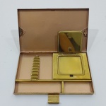 Antiga Caixa Cigarreira e Porta Maquiagem, Década de 40, Em Metal Dourado, Sem Marca Aparente, Com Pequenos desgastes pelo tempo e uso. Medidas: Altura: 1,5 cm, Largura: 10,5 cm, Comprimento: 16 cm, Peso: 360 g. 
