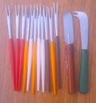 Onze garfos para fondue, acompanhados por uma faca para patê e um garfinho auxiliar.