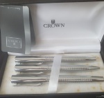 Conjunto de canetas Crown Capricci prateadas, com logo da Rede Globo, composto por três modelos: esferográfica, rollerball e tinteiro. As peças têm acabamento prateado com textura quadriculada no corpo e vêm em uma caixa preta elegante, ideal para presente.A Crown é reconhecida pela qualidade e durabilidade, tornando o kit uma opção premium para diferentes estilos e ocasiões de escrita- Funcionado, A tinteiro está sem carga.