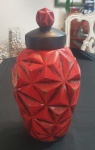 Vaso decorativo em Cerâmica Vermelha com Tampa Design Geométrico Vintage Este elegante vaso decorativo em cerâmica apresenta um design facetado com relevos geométricos, criando um jogo de luz e sombra que valoriza sua textura tridimensional. A peça é pintada em vermelho vivo com acabamentos envelhecidos, conferindo um ar retrô sofisticado.O destaque está na tampa preta com pegador em forma de losango facetado, harmonizando com o corpo da peça e acrescentando funcionalidade ao design. Ideal para compor ambientes modernos ou ecléticos, o pote também pode ser utilizado como objeto de coleção ou para armazenar pequenos itens.Material: Cerâmica esmaltadaCor predominante: Vermelho com detalhes escurecidos e tampa pretaEstilo: Retrô / Vintage com influência contemporânea, Decoração de salas, aparadores, cozinhas ou espaços gourmet  Apresenta leves desgastes na pintura, característicos de peças com estilo envelhecido - Altura: 40 cm