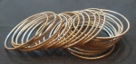 Conjunto é composto por 24 pulseiras rígidas e finas, em tom dourado, com textura em relevo diagonal que cria um efeito moderno e elegante. As peças podem ser usadas individualmente para um visual discreto ou em conjunto, compondo um estilo mais marcante e sofisticado.