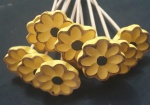 Conjunto com 10 unidades. Enfeites em formato de margaridas feitas em madeira, com pétalas amarelas, miolo escuro e bordas suavemente realçadas em tom mais escuro. Cada flor é fixada em um palito de madeira, ideal para uso como topper decorativo em doces, bolos, arranjos ou outros artesanatos. Peças delicadas e com acabamento artesanal.Altura: 40 cm.