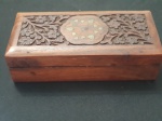 Caixa em madeira  entalhada, tampo com reserva e detalhes ao centro -. Dimensões 19x9x5,5 cm