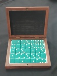 Caixa de dominó com peças verdes, possivelmente feitas em baquelite. Acompanha estojo de madeira e apresenta acabamento clássico e bem conservado.